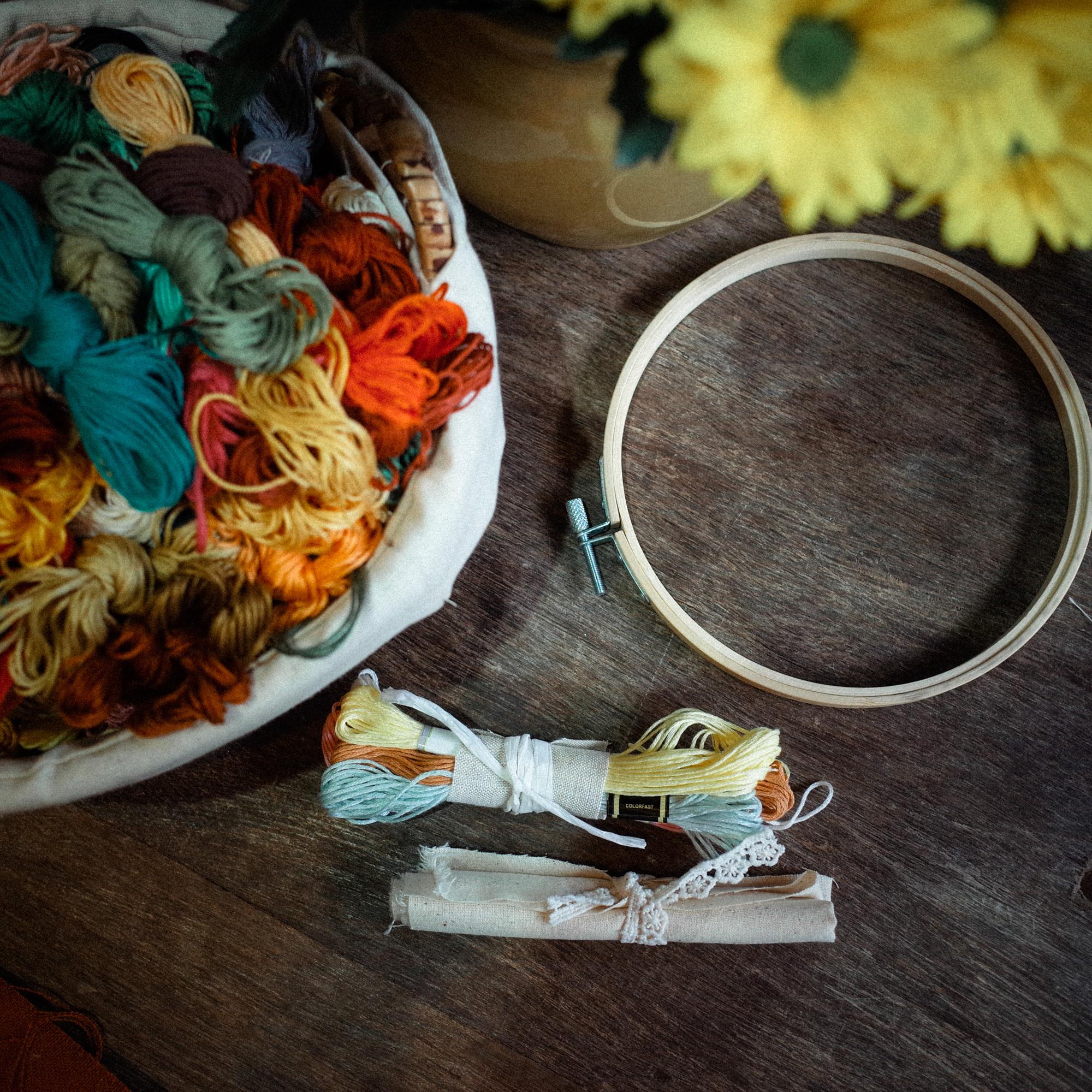 Workspace with embroidery hoops, spools of thread and gold needles